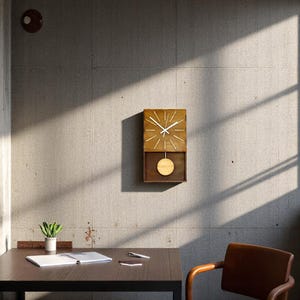 Puede incluir: Un reloj de pared rectangular de madera con esfera clara, manecillas blancas para horas y minutos, y marcadores blancos finos para cada hora. Debajo de la esfera hay un compartimento abierto con un p&eacute;ndulo circular de madera suspendido.