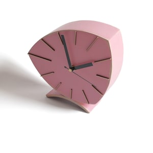 Peut inclure: Une horloge en bois rose avec des aiguilles noires et des accents dor&eacute;s. L'horloge a la forme d'un &eacute;ventail et pr&eacute;sente un design unique.