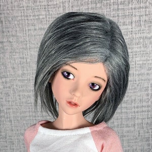 May include: A doll with short, gray hair and purple eyes wearing a pink and white shirt.