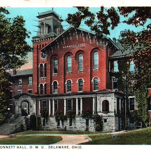 May include: A vintage postcard depicting a red brick building with a tower. The building is labeled "Dormitory, Monnett Hall, O.W.U., Delaware, Ohio".