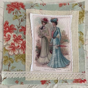 May include: A fabric collage featuring a vintage illustration of two women in period dresses. The illustration is framed by layers of fabric, including floral patterns in red and blue, and a strip of lace. The overall aesthetic is vintage and feminine.