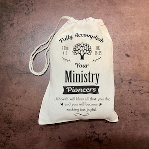 May include: White drawstring bag with the text "Fully Accomplish Your Ministry Pioneers" and the Bible verses "2 Tim 4:5" and "De 16:15". The bag also has a tree graphic and the text "Jehovah will bless all that you do: and you will become nothing but joyful."