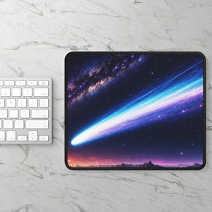 May include: A rectangular mouse pad featuring a vibrant space scene with a bright blue and purple comet streaking across a dark starry sky, a distant galaxy, and a silhouette of a mountain range along the bottom edge, finished with a black border.