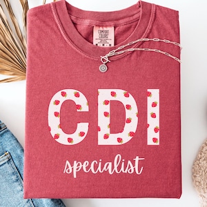 May include: A red t-shirt with the letters "CDI" in white with a strawberry pattern. The text "specialist" is written below the letters.