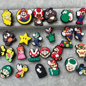May include: A selection of colourful shoe charms featuring characters from the Super Mario video game series. Includes Mario, Luigi, Princess Peach, Yoshi, and other recognisable figures.