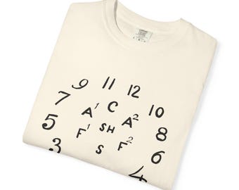 May include: Cream-colored t-shirt with a black clock face design. The clock face features numbers and letters in a unique arrangement, with the text "EXPRESS COLORS" on the tag.