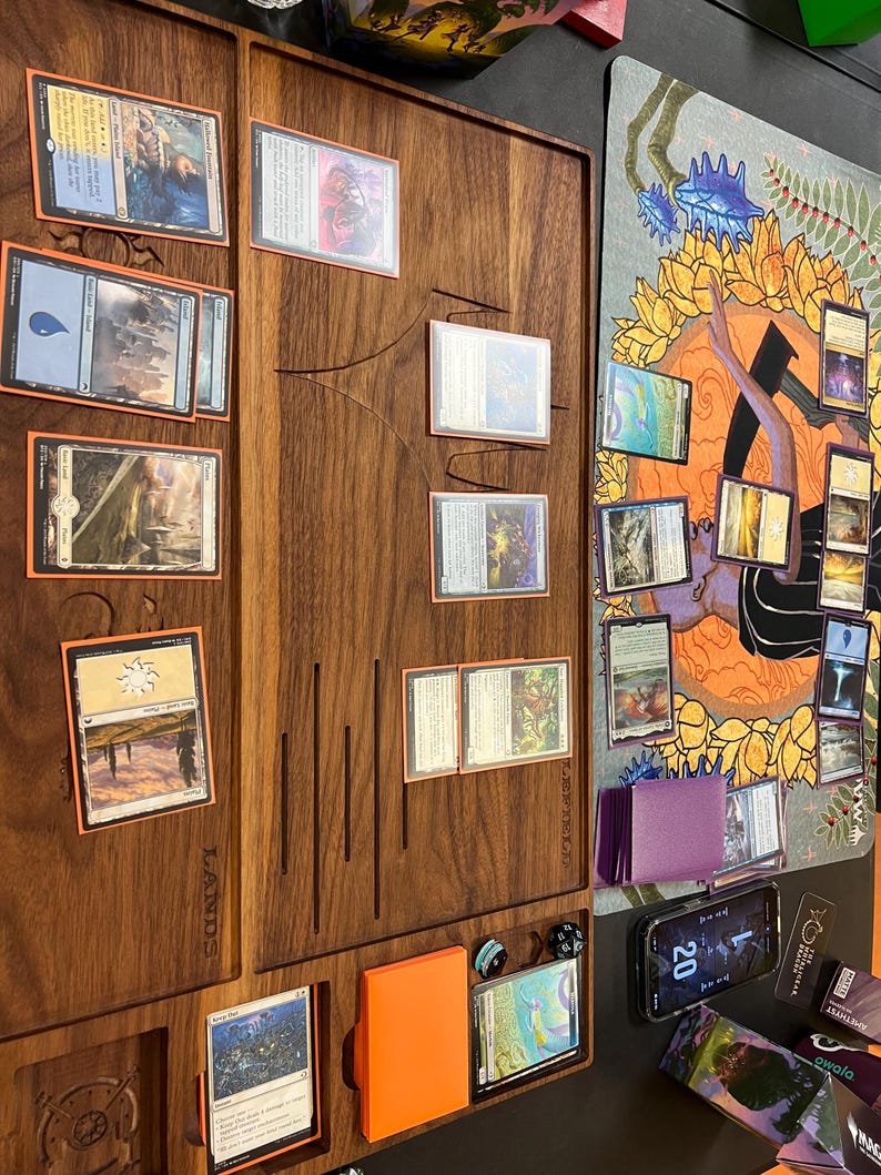 May include: A wooden game board with card slots and a play mat. Various Magic: The Gathering cards are arranged on the board. An orange card holder and dice are also visible. The word "LANDS" is printed on the board.