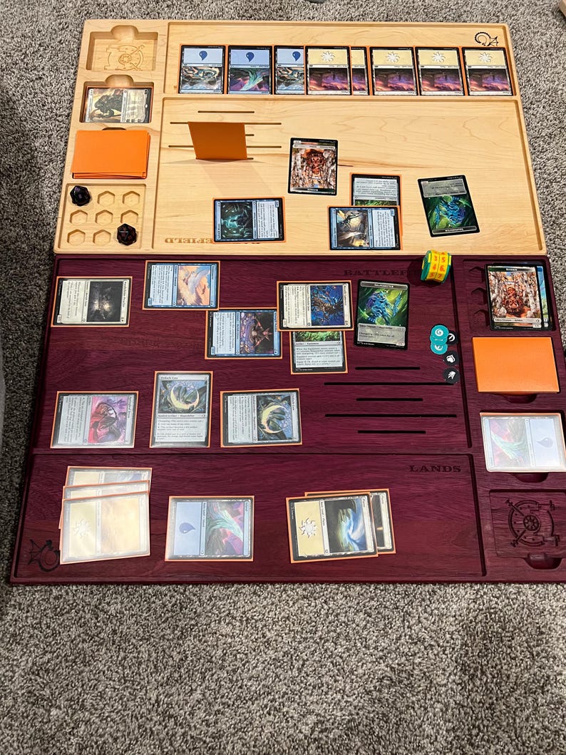May include: Wooden game board with two levels, one light wood and one dark wood. The top level holds cards, dice, and an orange card holder. The bottom level has card slots and a dice area. Cards are arranged on both levels.