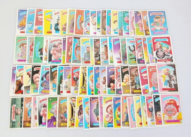 May include: A collection of Garbage Pail Kids trading cards, featuring various cartoon characters with humorous and grotesque designs. The cards have colorful borders and unique illustrations.
