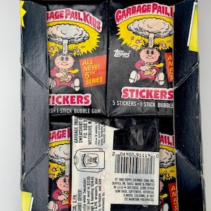 May include: A box of Garbage Pail Kids stickers with a black background and a cartoon character on the front. The box says "All New! 5th Series" and "5 Stickers - 1 Stick Bubble Gum".