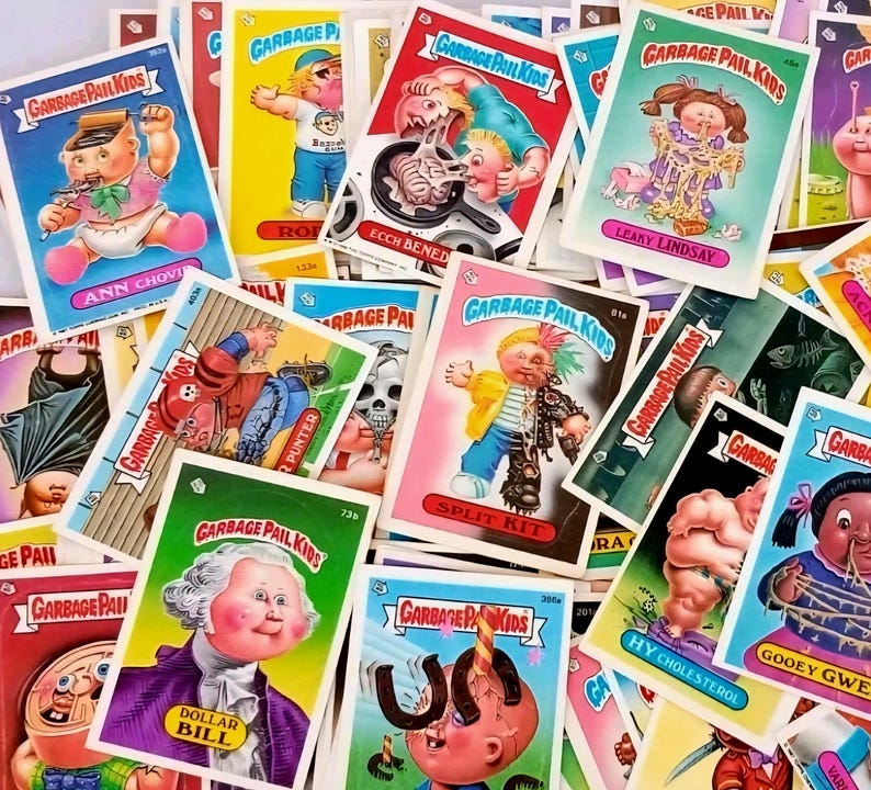 May include: A collection of Garbage Pail Kids trading cards. The cards feature colorful, cartoonish illustrations of grotesque characters with humorous names. The cards are scattered, showcasing various designs and titles like "Ann Chovy" and "Leaky Lindsay".