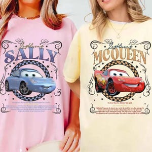 Puede incluir: Dos camisetas, una rosa y otra amarilla, cada una con un dise&ntilde;o de coche de dibujos animados. La camiseta rosa muestra "Lightning Sally" con un coche azul, mientras que la camiseta amarilla muestra "Lightning McQueen" con un coche rojo.