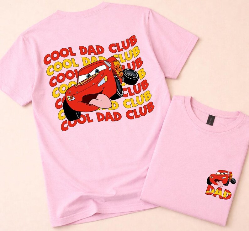 May include: Two light pink t-shirts. One shirt features a large graphic of a red race car with the text "COOL DAD CLUB" in yellow and red. The other shirt has a smaller version of the car graphic with the word "DAD".