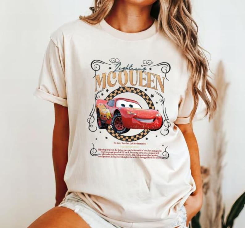 Puede incluir: Una camiseta beige con un dise&ntilde;o de Rayo McQueen de la pel&iacute;cula Cars. El dise&ntilde;o incluye el texto "Lightning McQueen" y una imagen estilizada del coche de carreras rojo. La camiseta tiene mangas cortas.