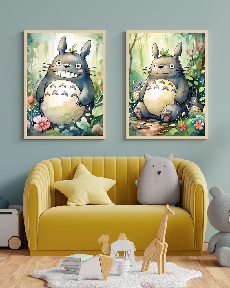 May include: Two framed watercolor prints of the character Totoro from the animated film My Neighbor Totoro. The prints feature the character in a forest setting. The prints are displayed above a yellow sofa with decorative pillows.