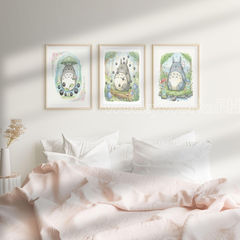 May include: Three framed watercolor prints featuring the character Totoro from the animated film My Neighbor Totoro. Each print depicts a different scene with Totoro in a forest setting, surrounded by nature and whimsical details. The frames are light-colored wood.