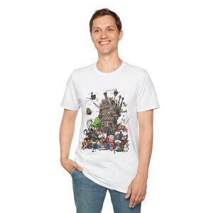 May include: White t-shirt featuring a detailed illustration of a fantastical castle with numerous characters. The artwork includes a variety of creatures and figures in a colorful, whimsical style. The shirt is made of a soft material.