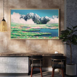 Pu&ograve; includere: Una stampa artistica incorniciata raffigura una serena scena di montagna. Vette innevate si ergono su una valle piena di fiori rosa e un lago blu. L'opera d'arte &egrave; esposta sopra una scrivania di legno con due sedie.
