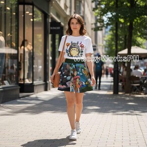 K&ouml;nnte beinhalten: Ein wei&szlig;es T-Shirt mit einer Cartoonfigur und ein farbenfroher Rock mit einer Fantasieszene. Der Text "WackyWorksPH" ist auf das T-Shirt gedruckt. Die Person tr&auml;gt eine braune Tasche und wei&szlig;e Turnschuhe.