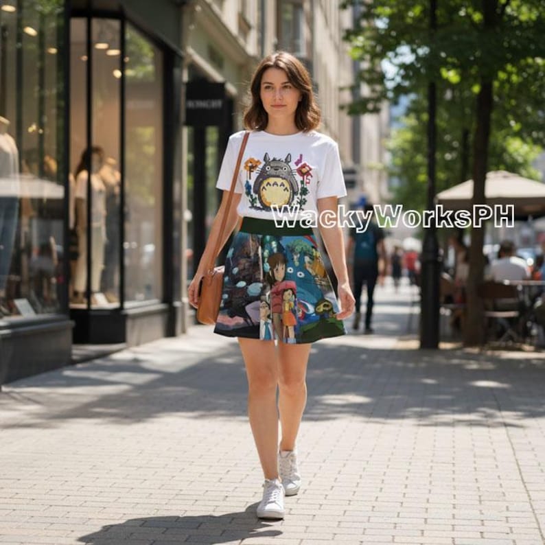 K&ouml;nnte beinhalten: Ein wei&szlig;es T-Shirt mit einer Cartoonfigur und ein farbenfroher Rock mit einer Fantasieszene. Der Text "WackyWorksPH" ist auf das T-Shirt gedruckt. Die Person tr&auml;gt eine braune Tasche und wei&szlig;e Turnschuhe.
