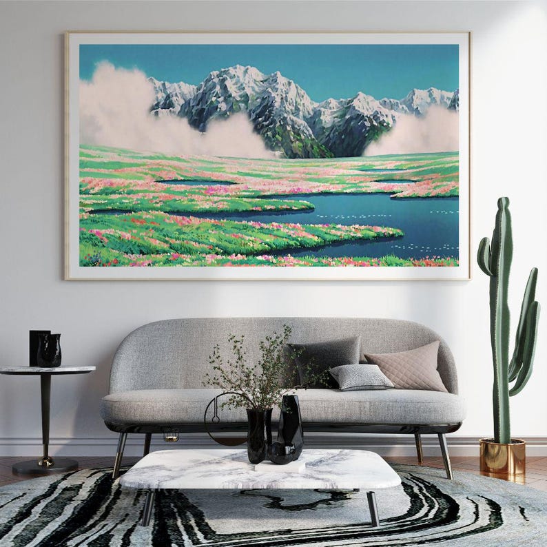 Pu&ograve; includere: Una stampa artistica incorniciata raffigura un sereno paesaggio montano. Vette innevate si ergono su una valle piena di fiori colorati e un lago blu. L'opera d'arte &egrave; appesa sopra un divano grigio in un moderno soggiorno.