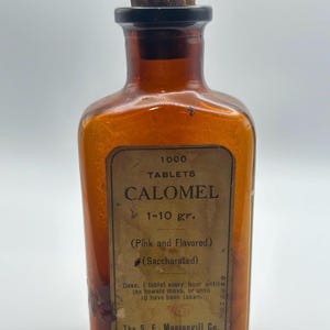May include: An antique amber glass bottle with a cork stopper. The label reads "1000 Tablets Calomel" with dosage instructions. The bottle is labeled "Pink and Flavored" and "Saccharated". The label also includes the manufacturer's name, "The S. E. Massengill Co."