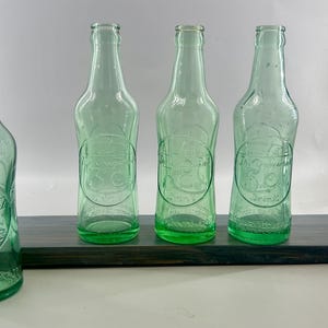 Three aqua soda bottles standing side by side against a light background.