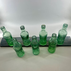 Overhead arrangement of the seven bottles showing their mouths, necks, and round bases.