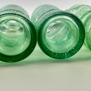 Bottom views of two bottles showing circular bases and molded factory marks.