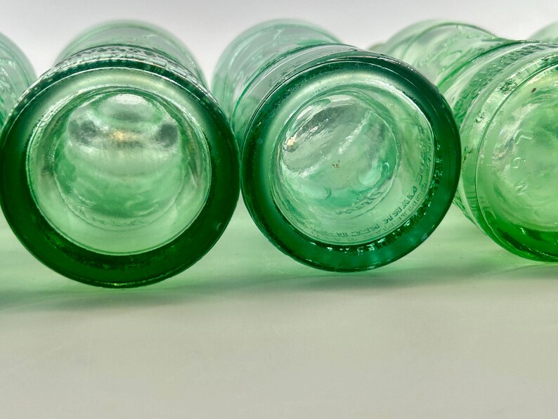 Bottom views of two bottles showing circular bases and molded factory marks.