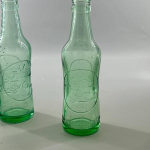 Two antique aqua bottles shown upright, highlighting differences in shape and embossing.