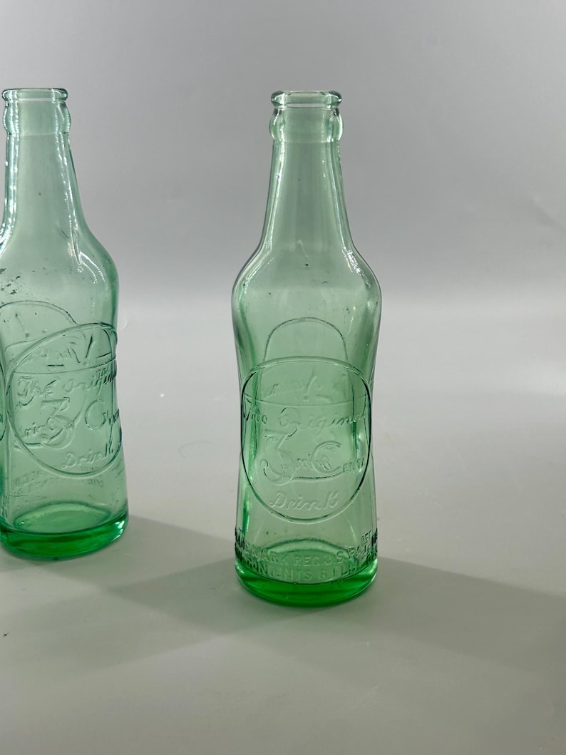 Two antique aqua bottles shown upright, highlighting differences in shape and embossing.
