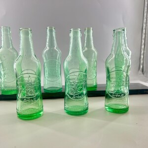 Studio group view of the seven aqua soda bottles arranged in two rows.