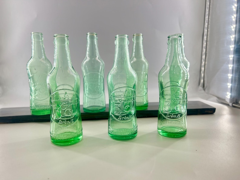 Studio group view of the seven aqua soda bottles arranged in two rows.