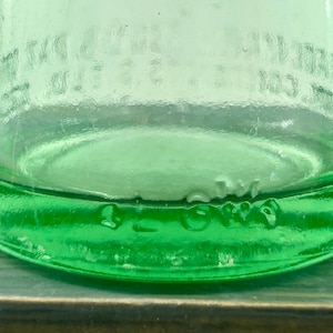 Close-up of an aqua bottle heel and base showing molded letters and small glass bubbles.