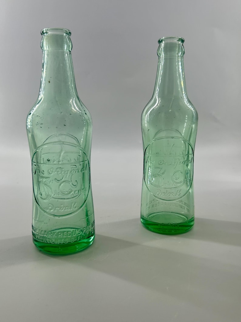 Two bottles shown from front and back to compare embossing and plain glass.