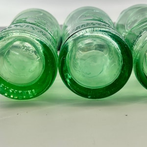 Close bottom views of two bottles with thick aqua glass and circular mold patterns.