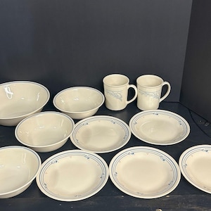May include: A set of white ceramic dishes with a blue floral pattern. The set includes bowls, plates, and mugs.