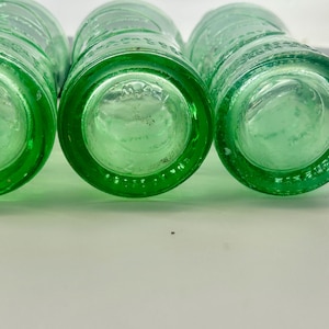 Bottom views of three aqua bottles showing different molded rings and base markings.