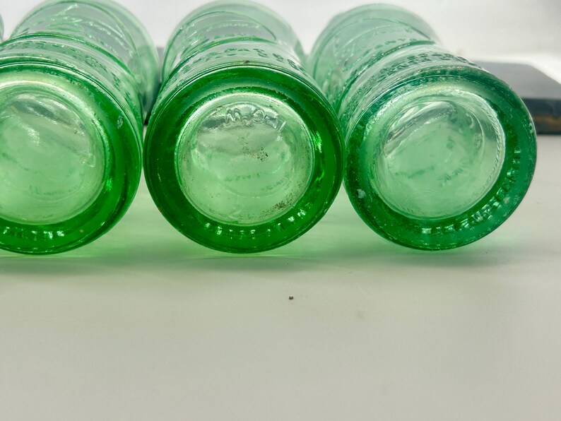 Bottom views of three aqua bottles showing different molded rings and base markings.