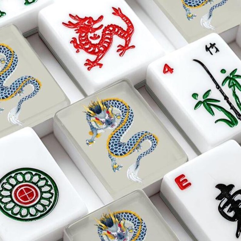 May include: A collection of rectangular mahjong tiles featuring various designs including a red dragon, a blue and yellow dragon, green bamboo stalks, a circular floral pattern, and the letter E, all set against a white or light gray background.