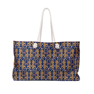 Peut inclure: Grand sac fourre-tout avec un fond bleu marine et un motif répété de guépards dorés, de fleurs roses et d'étoiles blanches. Le sac a des poignées en corde blanche et des accents blancs.