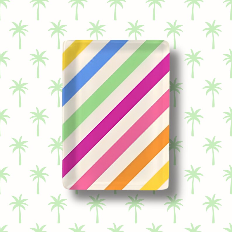 May include: A rectangular glass tray featuring a vibrant pattern of diagonal stripes in shades of blue, light green, magenta, pink, orange, and yellow against a cream-colored background, with rounded corners and a smooth, glossy finish.