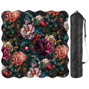 May include: A floral yoga mat with a dark background and a pattern of large, colorful flowers in shades of pink, red, and white. A black carrying bag with a shoulder strap is next to the mat.