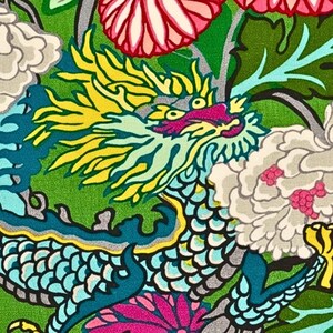 May include: A vibrant, detailed illustration of a dragon amidst floral elements. The dragon features a teal body, yellow mane, and pink accents, set against a green backdrop with white and pink flowers. The design has a bold, colorful aesthetic.