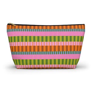 May include: A rectangular cosmetic bag with a vibrant striped pattern. The design features vertical stripes in shades of pink, green, orange, and blue. The bag has a black zip and a gold-coloured zip pull.