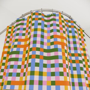 May include: A colorful shower curtain with a repeating checkered pattern in shades of orange, green, blue, pink, and yellow. The curtain hangs from a curved, silver-colored shower rod.