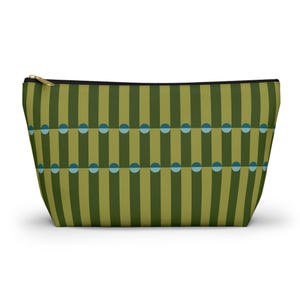 May include: A rectangular cosmetic bag with a vertical striped pattern in shades of green and olive. The design includes rows of teal half-circles. The bag has a black zipper and a gold-coloured zip pull.