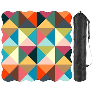 May include: A square picnic blanket with a scalloped edge featuring a geometric pattern of triangles in shades of orange, pink, blue, yellow, brown, and cream, accompanied by a black cylindrical carrying bag with an adjustable shoulder strap.