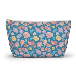 May include: A blue zippered pouch featuring a repeating pattern of seashells in pink, yellow, orange, and blue. The pouch has a gold-coloured zip.